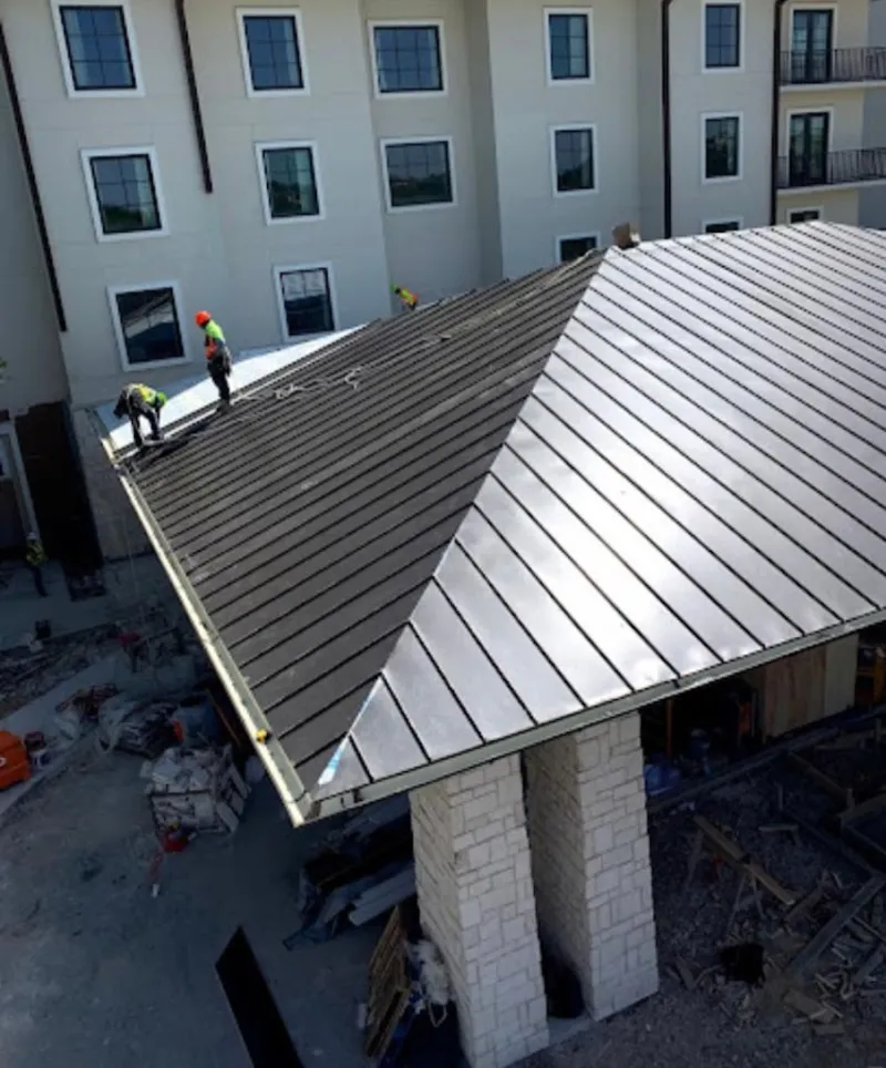 Crew installing standing seam metal roof panels on a commercial project in Elwood